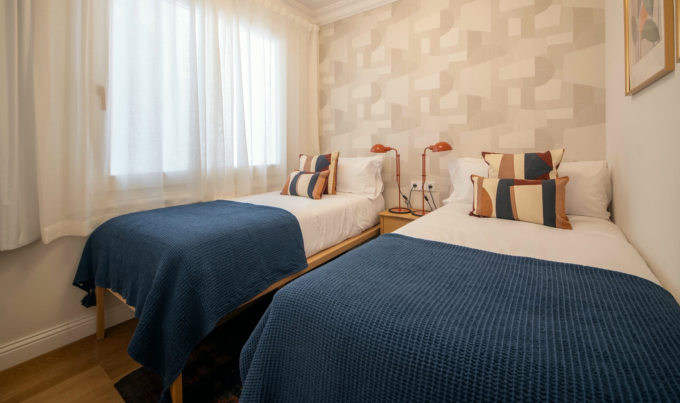 Suite Alba second bedroom with two single beds beside a softly curtained window