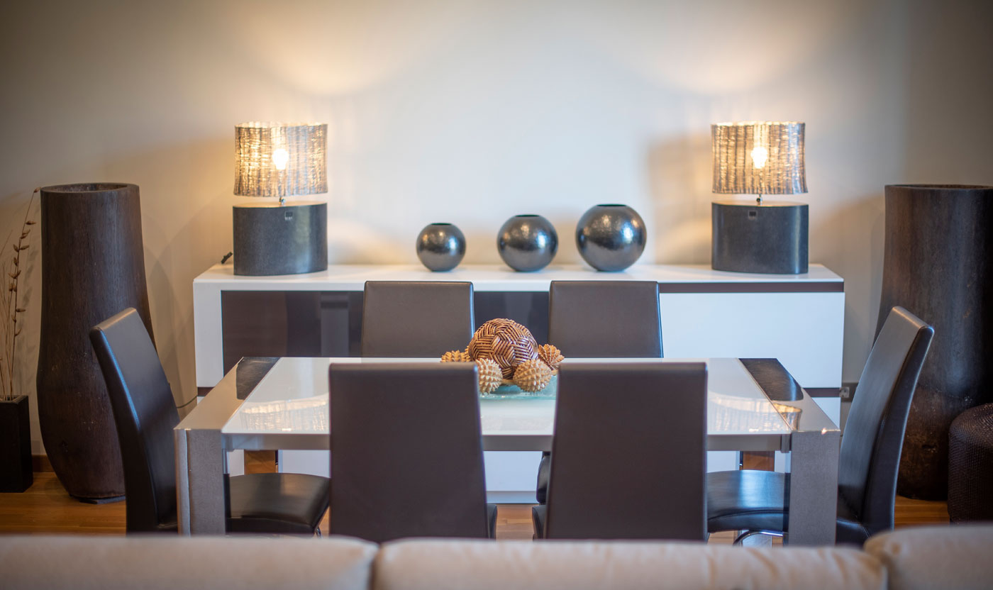 White dining table with six chairs beside the Suite Sagrada balcony windows