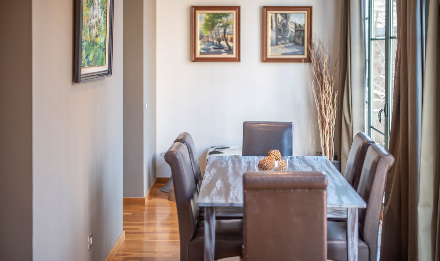 Suite Sol&eacute;a dining room framed by gallery windows and artwork
