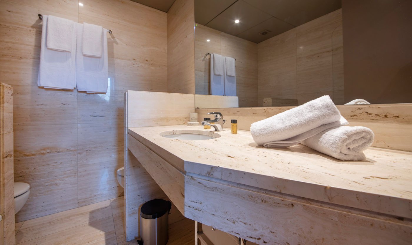 Stone vanity, mirror and towels in the Suite Sol&eacute;a principal bathroom