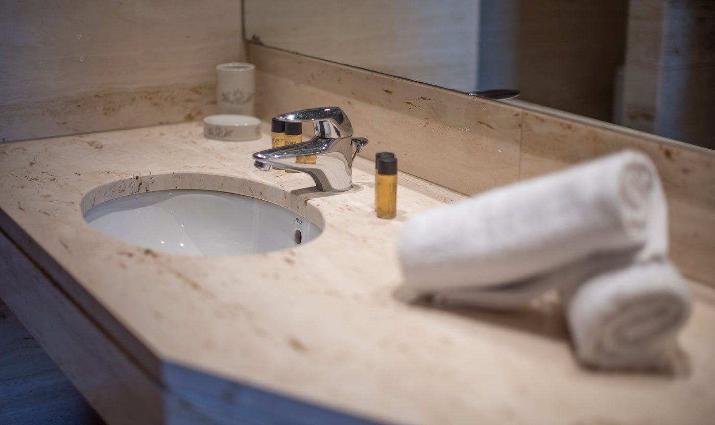 Stone sink and folded towels in the Suite Sol&eacute;a principal bathroom