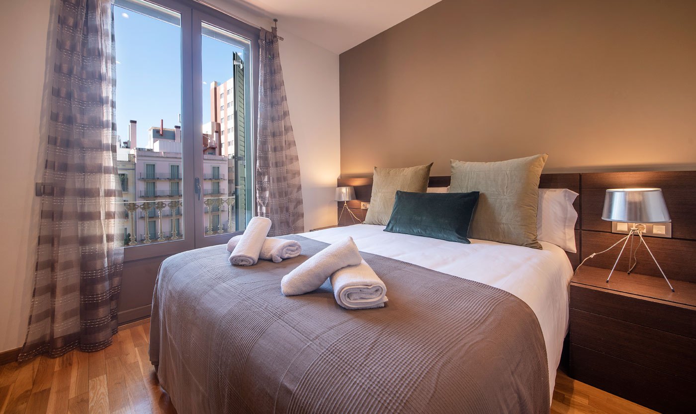 Suite Sol&eacute;a principal bedroom with a queen bed, folded towels and city-facing window