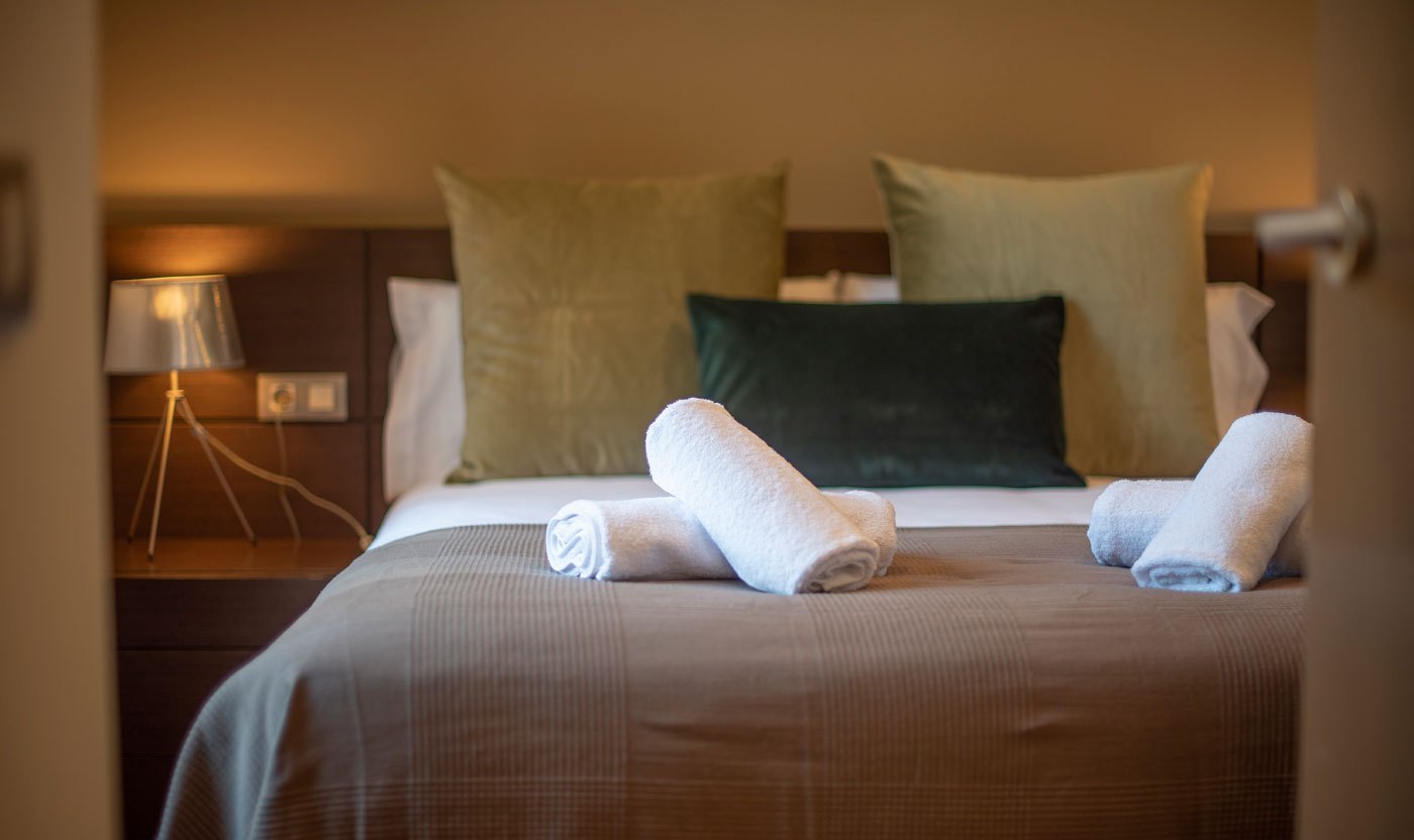 Queen bed, cushions and folded towels in the Suite Sol&eacute;a principal bedroom