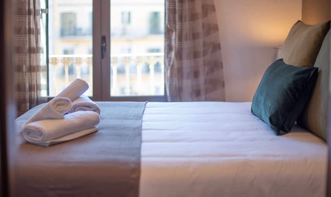 Queen bed and city view through the Suite Sol&eacute;a principal bedroom window