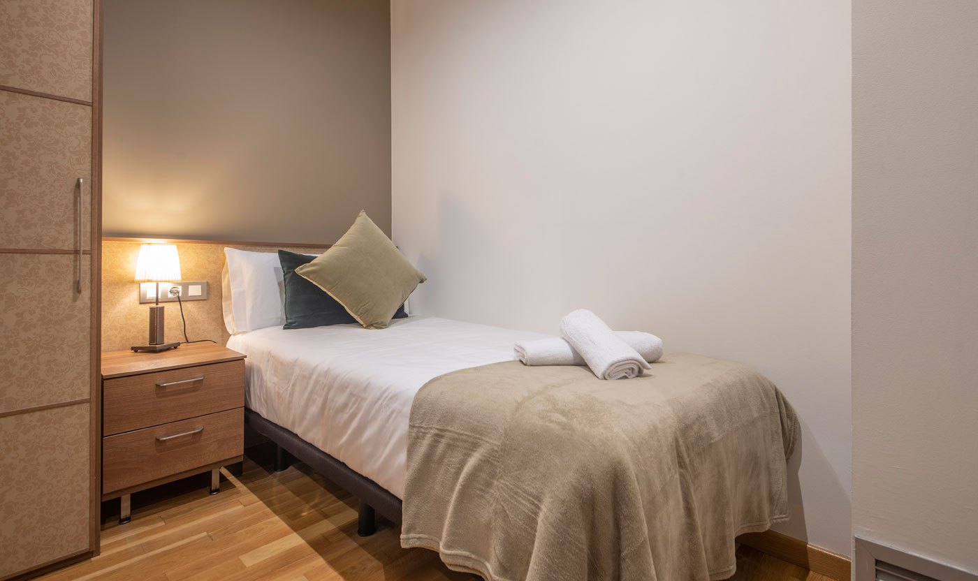 Third bedroom in Suite Sol&eacute;a with a single bed, bedside lamp and wardrobe